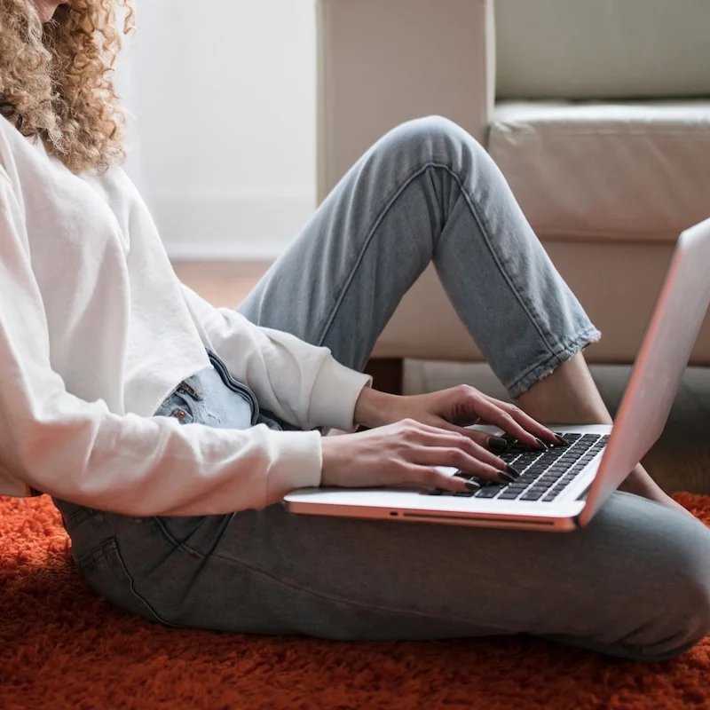 Woman using a laptop while sitting on the floor